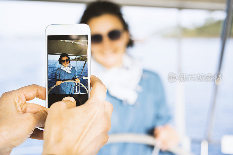 Taking photo of woman sailing with mobile phone